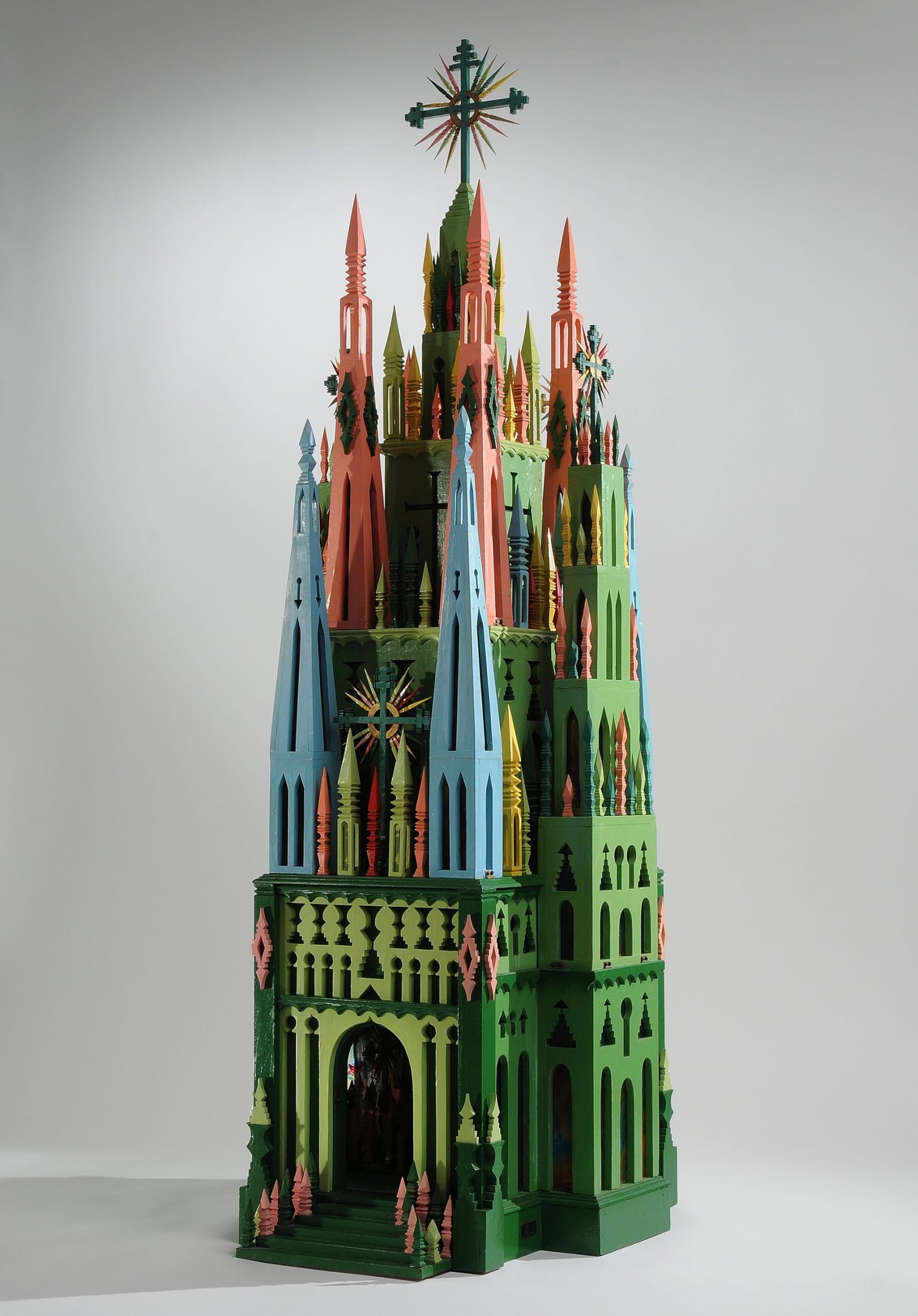 an elaborate wood carved cathedral in green, pink, and blue