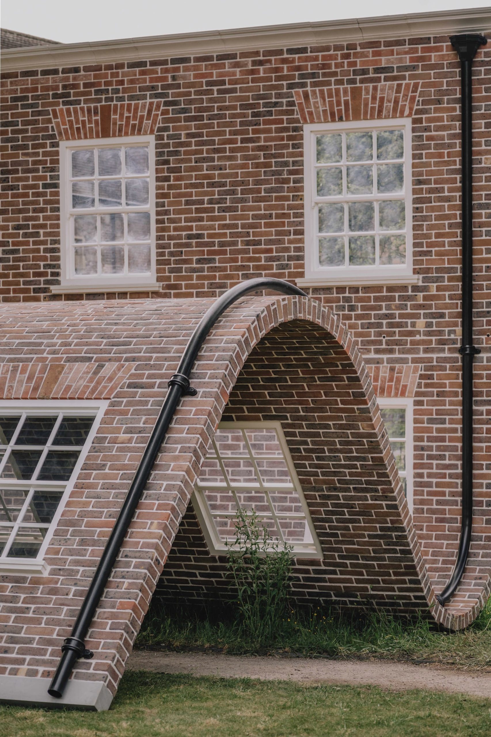 a detail of a public artwork resembling a curving brick townhouse facade