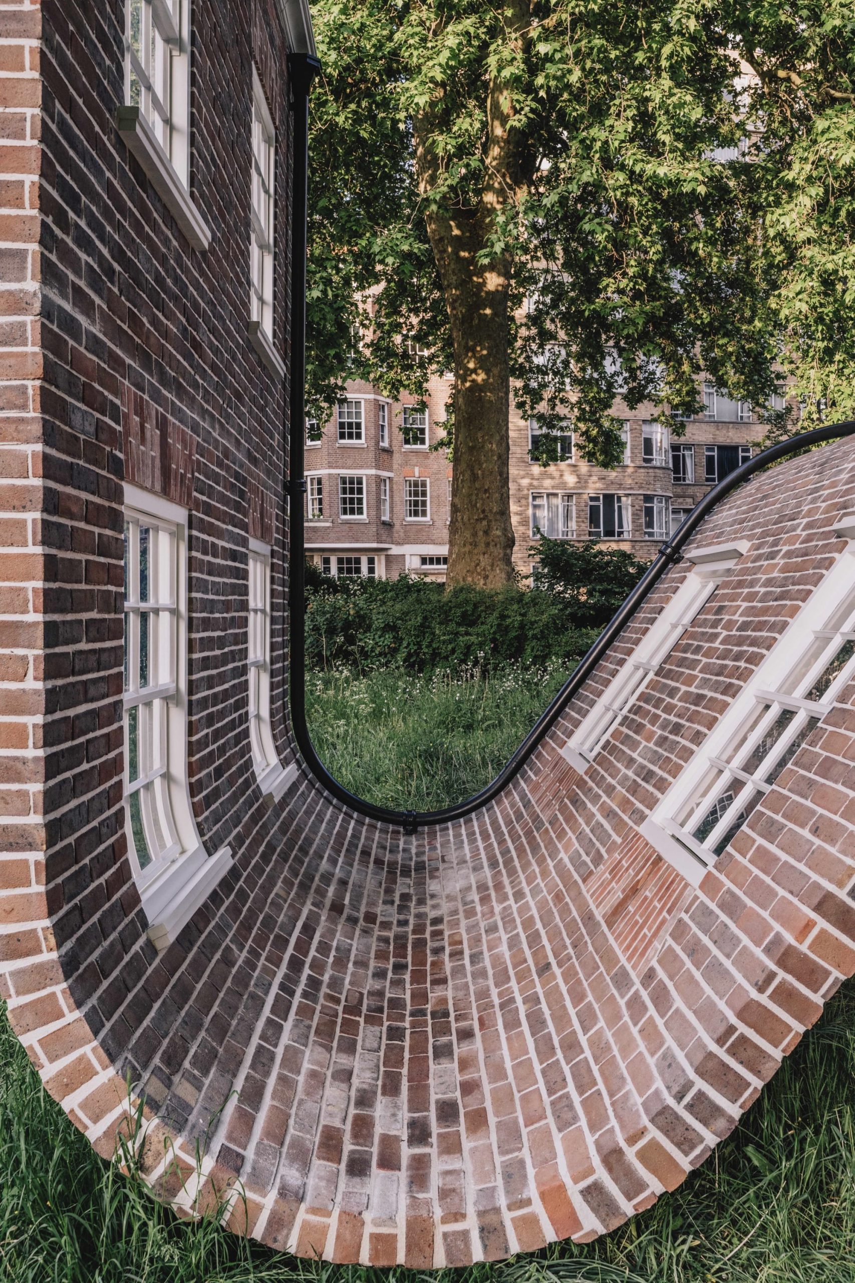 a detail of a public artwork resembling a curving brick townhouse facade