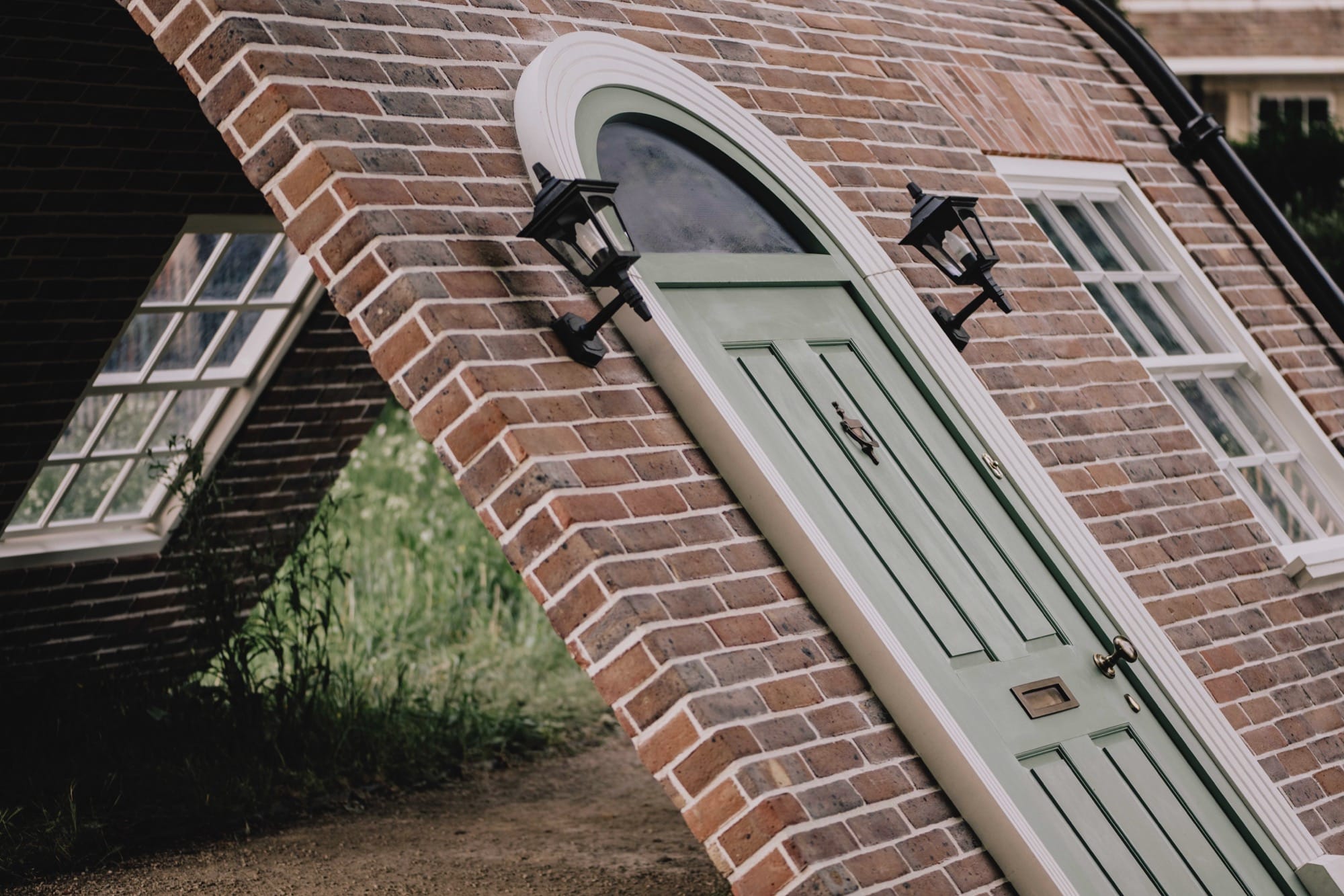 a detail of a public artwork resembling a curving brick townhouse facade