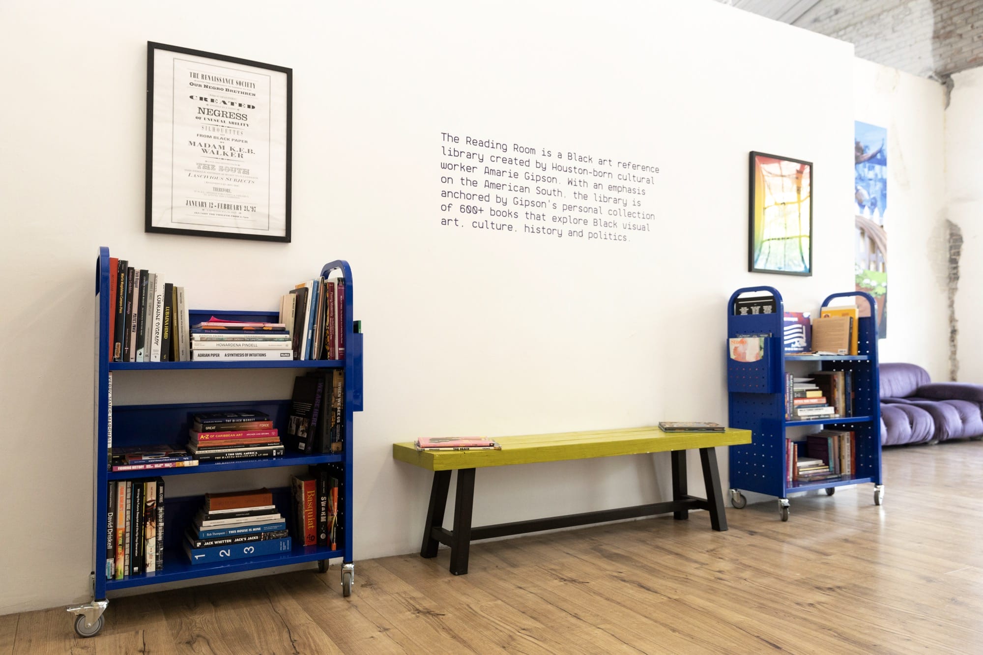 two blue library carts with books and a bench in between them