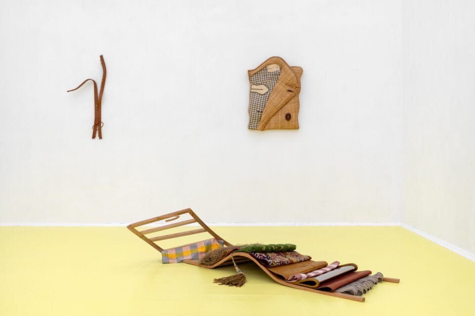 an installation view of three abstract sculptures in a white gallery with a yellow floor