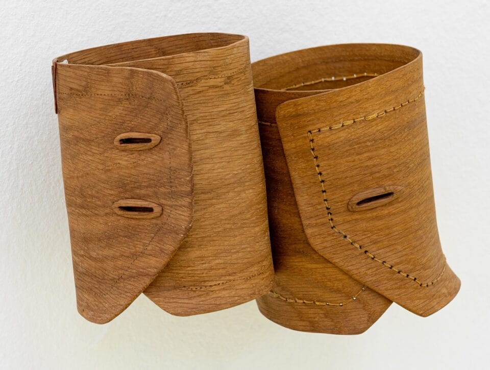 an abstract, wooden wall sculpture resembling two shirt cuffs
