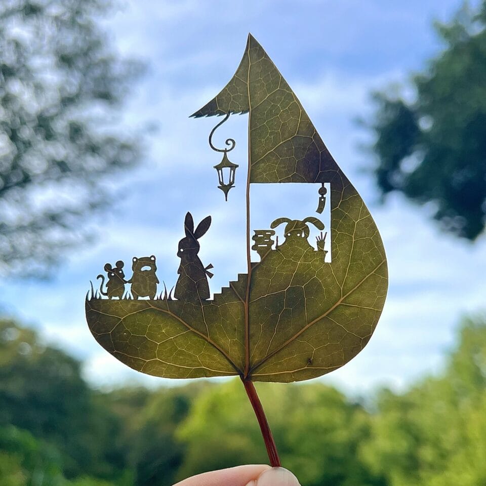 a cut leaf artwork of a rabbit family outside a house