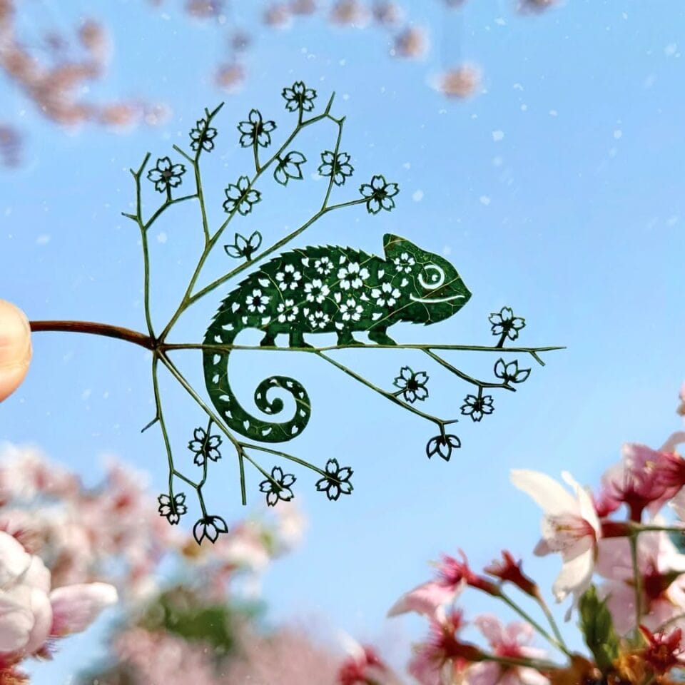 a cut leaf artwork of a chameleon on a branch