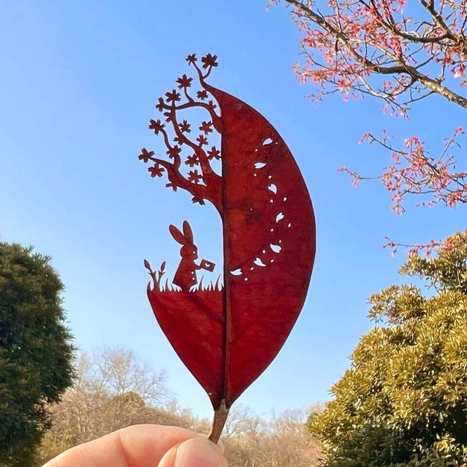 a cut leaf artwork of a rabbit under a tree