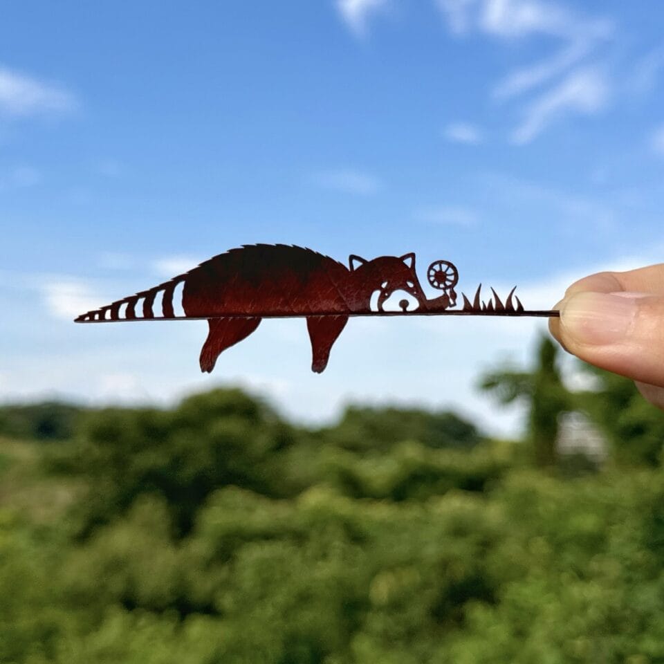 a cut leaf artwork of a relaxing raccoon